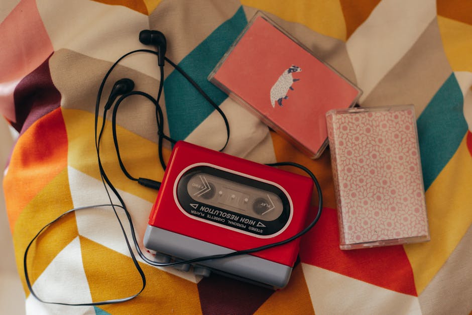 Vintage cassette player with earphones and tapes on colorful fabric.